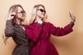 happy two smiling girls making selfie photo on smartphone on beige background Royalty Free Stock Photo