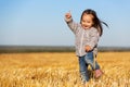 Happy two year old girl walking in a summer harvested field