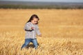 Happy two year girl walking in a summer harvested field