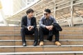 Two businessman sit on the stairs talking. Attractive businessmen sitting on stair at outdoor in city after work