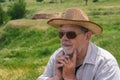 Happy Ukrainian countryman in straw hat and sunglasses against hilly spring pasture Royalty Free Stock Photo