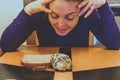 Happy yet undecided young adult woman decides between a blueberry scone or a piece of toast for breakfast, while sitting at table