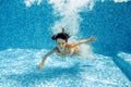 Happy underwater child jumps to swimming pool