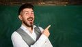 Happy university teacher near chalkboard pointing at copy space. High school. Smiling student in glasses in classroom Royalty Free Stock Photo