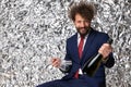 Happy unshaved man in navy blue suit holding champagne bottle and glasses Royalty Free Stock Photo