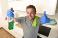 Happy unshaven man in rubber washing gloves holding detergent cleaning spray smiling confident