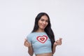 A happy and upbeat trans woman makes a heart finger gesture with both hands. Isolated on a white backdrop