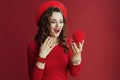 excited stylish woman in red dress and beret on red background