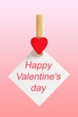 Happy Valentine`s Day clothespin with a heart and text on white paper on pink background Royalty Free Stock Photo