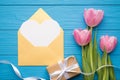 Happy valentine`s day concept. Flat lay top view photo of beautiful bouquet of tulips wrapped giftbox and golden open envelope