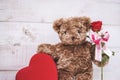 Happy Valentine`s day. A cute teddy bear plush holding a box of chocolate in red heart shape and red rose as a concept for Royalty Free Stock Photo