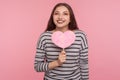 Happy Valentine`s day! Joyful pretty woman holding pink paper heart and looking at camera with toothy smile Royalty Free Stock Photo