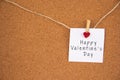 Happy Valentine`s day lettering on white paper pinned with glowing small heart pegs on cork board Royalty Free Stock Photo