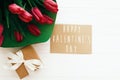 Happy Valentine`s Day text and beautiful red tulips with gift box on white wooden background. Happy valentine day greeting card Royalty Free Stock Photo