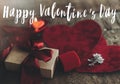 Happy Valentine`s day text on gift box, luxury earrings and red velvet hearts on rustic wood. Card