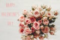 Happy Valentine`s Day text sign on pink roses bouquet on white background, top view. Valentines day floral greeting card Royalty Free Stock Photo