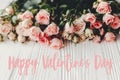 Happy Valentine`s Day text sign on pink small roses on wooden background in light. Tender Flowers image. Valentines day floral Royalty Free Stock Photo