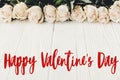 Happy Valentine`s Day text sign on white roses on wooden background, flat lay with space for text. Valentines day floral greetin Royalty Free Stock Photo