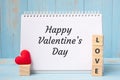 HAPPY VALENTINE `S DAY word on notebook and LOVE cubes with red heart shape decoration on blue wooden table background. Wedding, Royalty Free Stock Photo