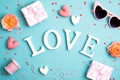 Happy Valentines Day flat lay composition. Word Love, gifts, hearts, sunglasses on blue background Royalty Free Stock Photo
