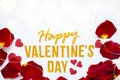 Happy Valentines Day gold text greeting card with red rose petals and shiny hearts bokeh on white wooden Background Royalty Free Stock Photo