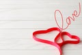 Red Satin Ribbon in Shape of Two Hearts on Wooden Background Royalty Free Stock Photo