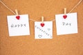 happy valentines day lettering on white paper pinned with 3 glowing heart pegs on cork board