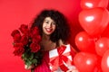 Happy Valentines day. Romantic girl with presents from lover, holding bouquet of roses and gift box, standing near cute Royalty Free Stock Photo