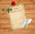 Old vintage paper, red rose and feather pen on wooden table Royalty Free Stock Photo