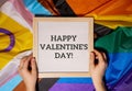 HAPPY VALENTINES DAY text frame on Rainbow LGBTQIA flag made from silk material. Symbol of LGBTQ pride month. Equal Royalty Free Stock Photo