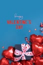 Happy Valentines Day text with gift box and red heart shape baloons on blue background. Valentines Day greeting card Royalty Free Stock Photo