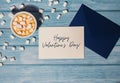 HAPPY VALENTINES DAY text Greeting card blue envelope with white cup of coffee and marshmallows on wooden blue Royalty Free Stock Photo