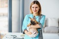 Happy veterinarian doctor hugs puppy in vet clinic. Empty space for text