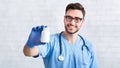 Happy veterinarian doctor in uniform holding bottle of pills at animal clinic, space for design Royalty Free Stock Photo