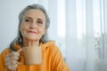 Happy vivacious middle-aged blond woman holding a cup of tea or coffee looking at the camera with a beaming warm smile Royalty Free Stock Photo