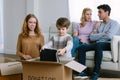 Happy volunteer caucasian family separating donations clothes in carton package donate to needy people in living room at home in Royalty Free Stock Photo