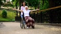 Happy volunteer pushing wheelchair with positive old lady, joyful female patient Royalty Free Stock Photo