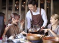 Waiter bring seafood and serving group of friends in restaurant