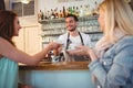 Happy waiter serving coffee to customer at cafeteria Royalty Free Stock Photo