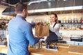 Happy waitress waring apron serving customer at counter in small family eatery restaurant