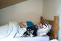 Happy waking up of a happy man lying with dog on the bed and stopping the alarm clock Royalty Free Stock Photo