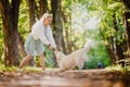 Happy walk with your beloved pet in autumn forest. Young woman in dress is playing with Labrodor Golden Retriever Royalty Free Stock Photo