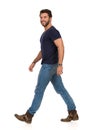 Happy Walking Man In Blue T-shirt, Jeans And Boots. Side View Royalty Free Stock Photo