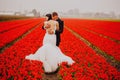 Happy wedding couple breathing fresh air in a colorful field with red flowers Royalty Free Stock Photo