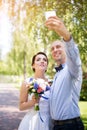 Happy wedding couple - bride and groom making selfie during wedding ceremony outdoors. Royalty Free Stock Photo