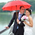 Happy wedding couple hiding from rain - portrait Royalty Free Stock Photo
