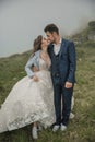 Happy wedding couple in the mountains. Bride and groom kiss. Easy style. Wedding dress and sneakers. Wedding photo session in Royalty Free Stock Photo