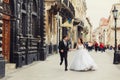 Happy wedding couple runs along the old street with great architecture