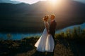 Happy wedding couple staying over the beautiful landscape with mountains