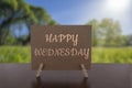 Happy Wednesday card on the table with sunny green forest background